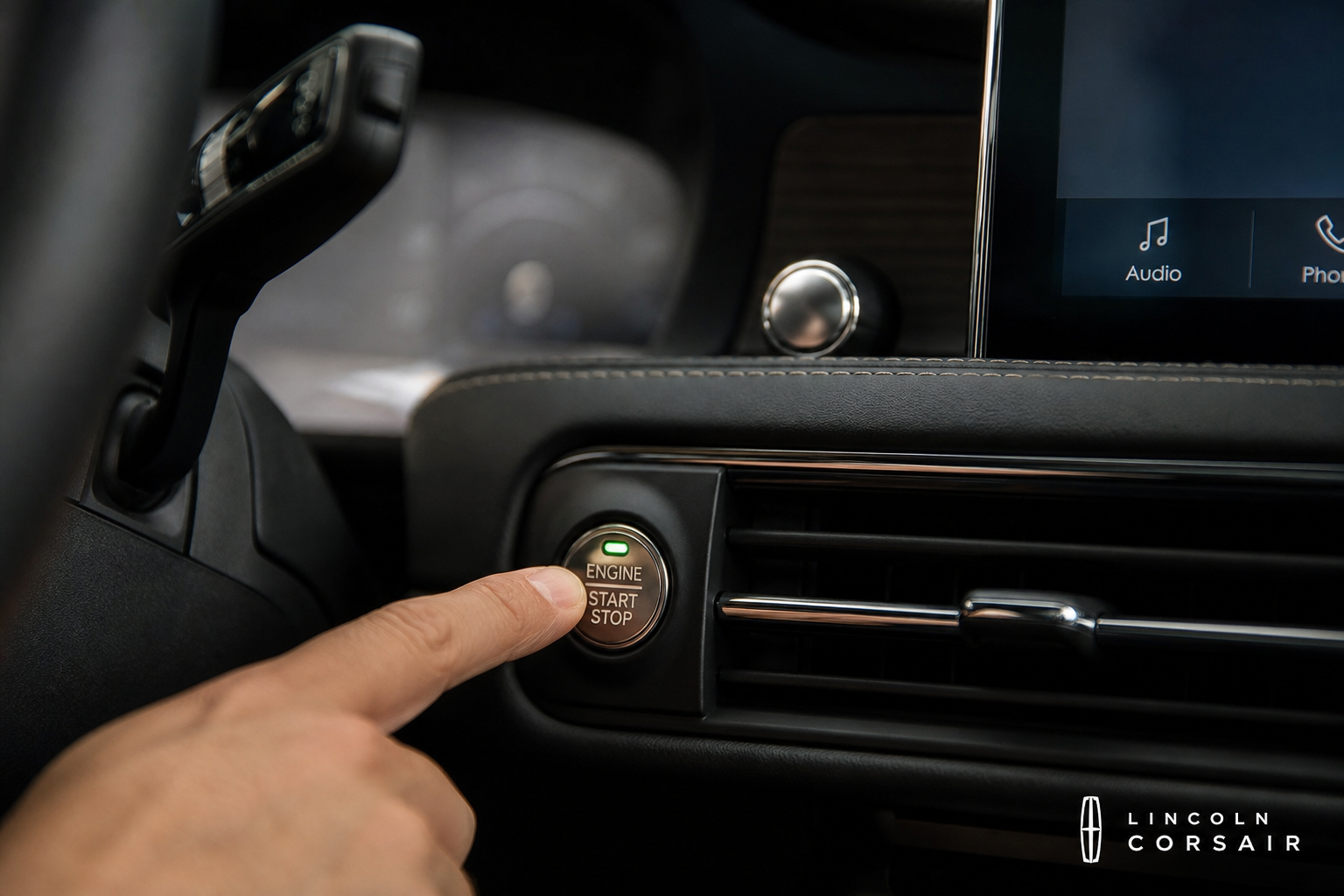 A finger pressing the auto start/stop disable button on the Lincoln Corsair center console