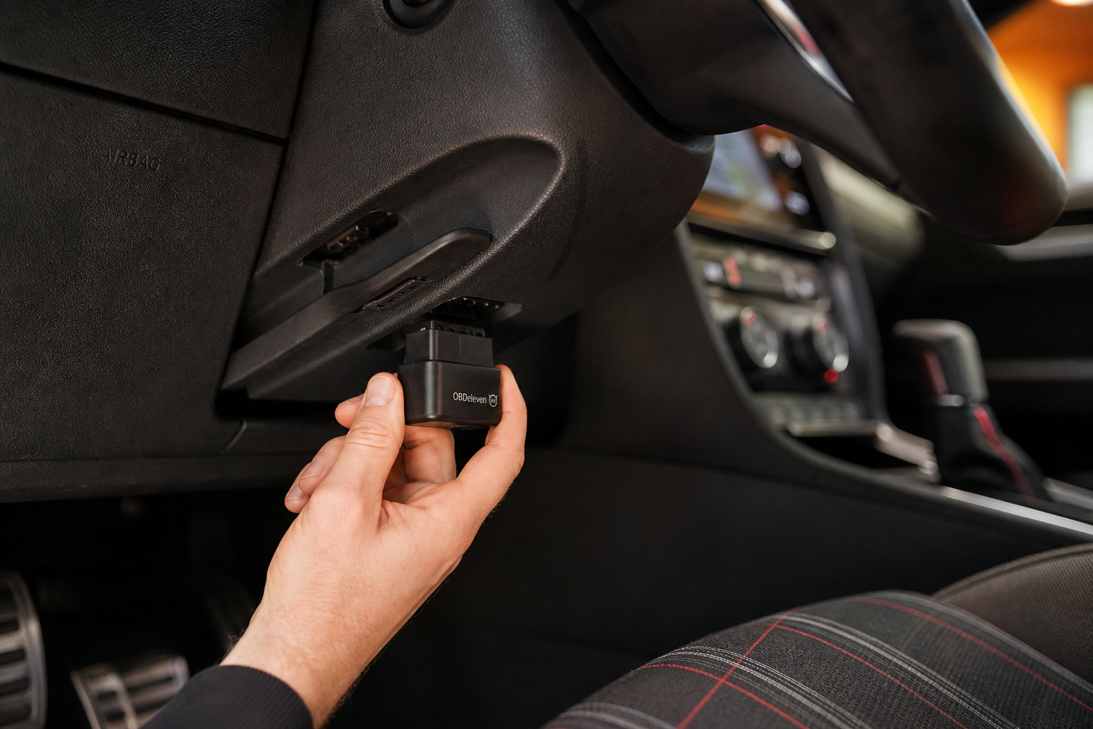 Hand plugging a start/stop eliminator module into the OBD2 port beneath the Golf GTI dashboard