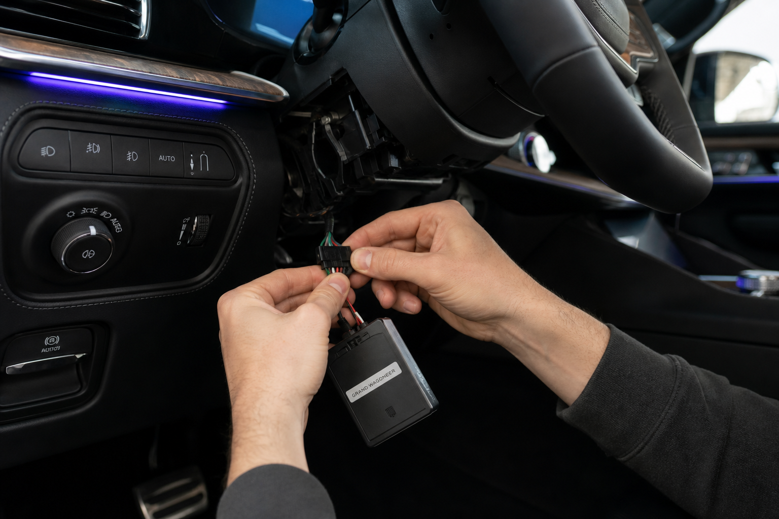 Hands connecting a wiring harness module under the dashboard of a Jeep Grand Wagoneer