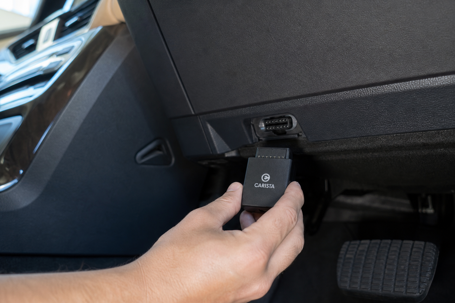 A hand inserting an OBD2 eliminator module under the dashboard of a Lexus RX