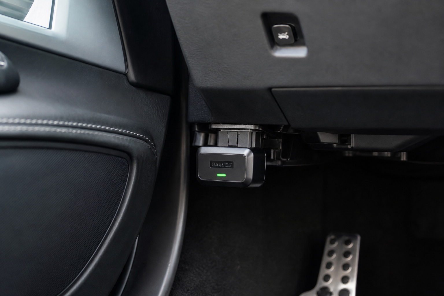 Small electronic start/stop eliminator module plugged into a car's OBD2 port under the dashboard