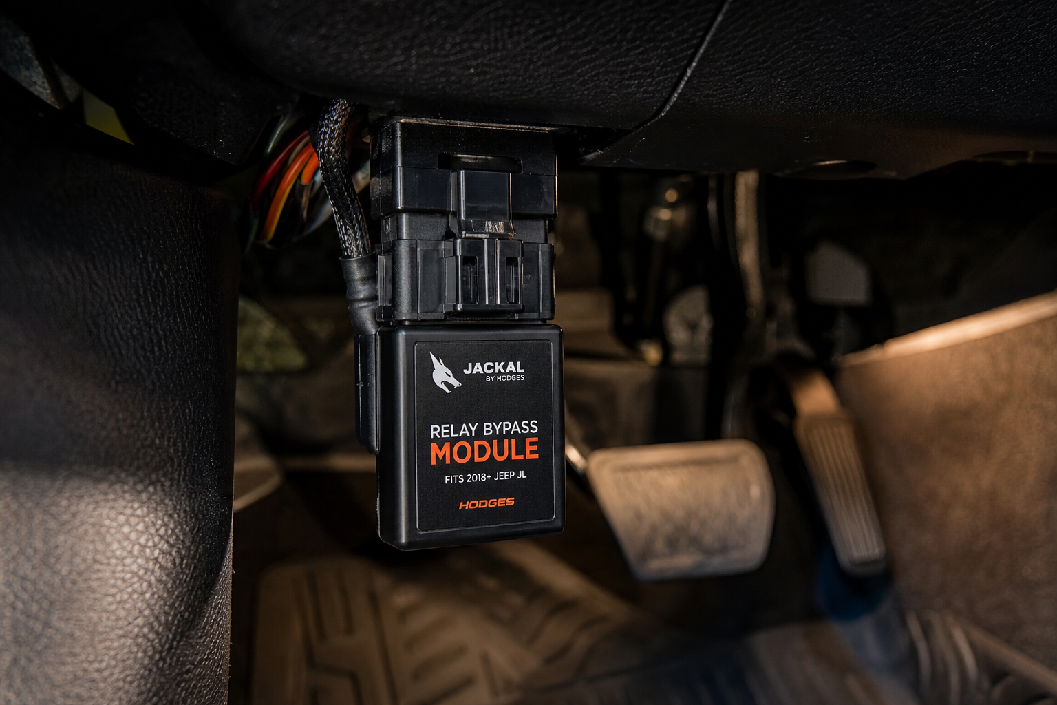 A start/stop eliminator module plugged into a connector under a car dashboard