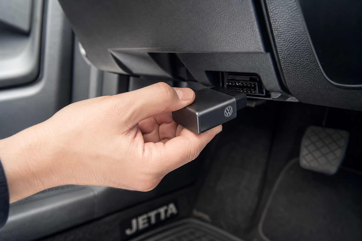 A start-stop eliminator module being plugged into the OBD2 port under a Volkswagen Jetta dashboard