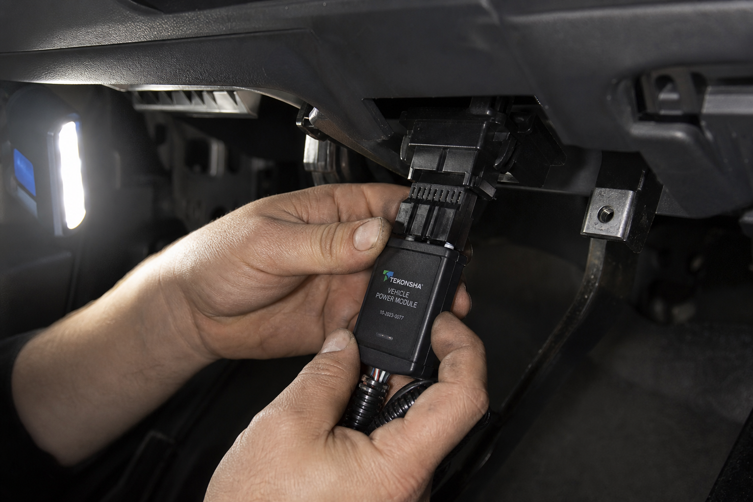 Small start/stop eliminator module being plugged into a connector under a truck dashboard