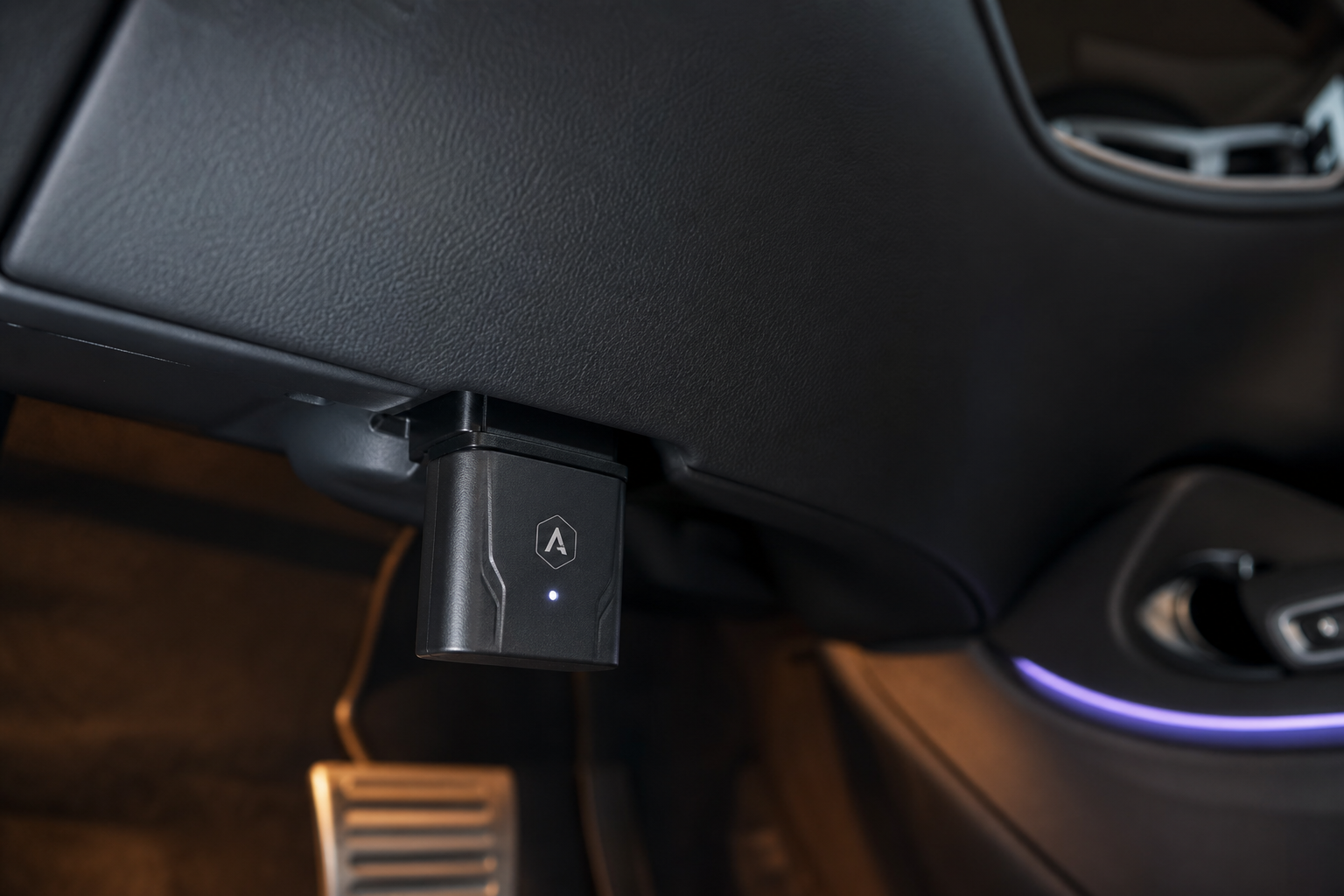 A start/stop eliminator module plugged into an OBD2 port under a Lexus RX dashboard