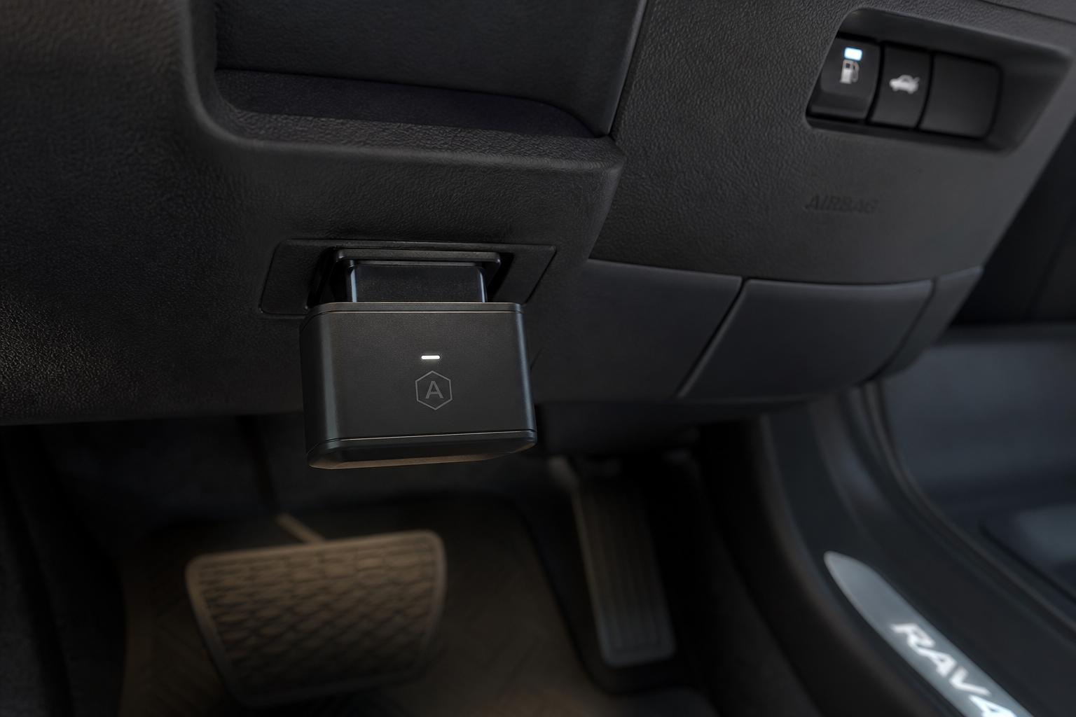 A start/stop eliminator module plugged into an OBD2 port under a Toyota SUV dashboard