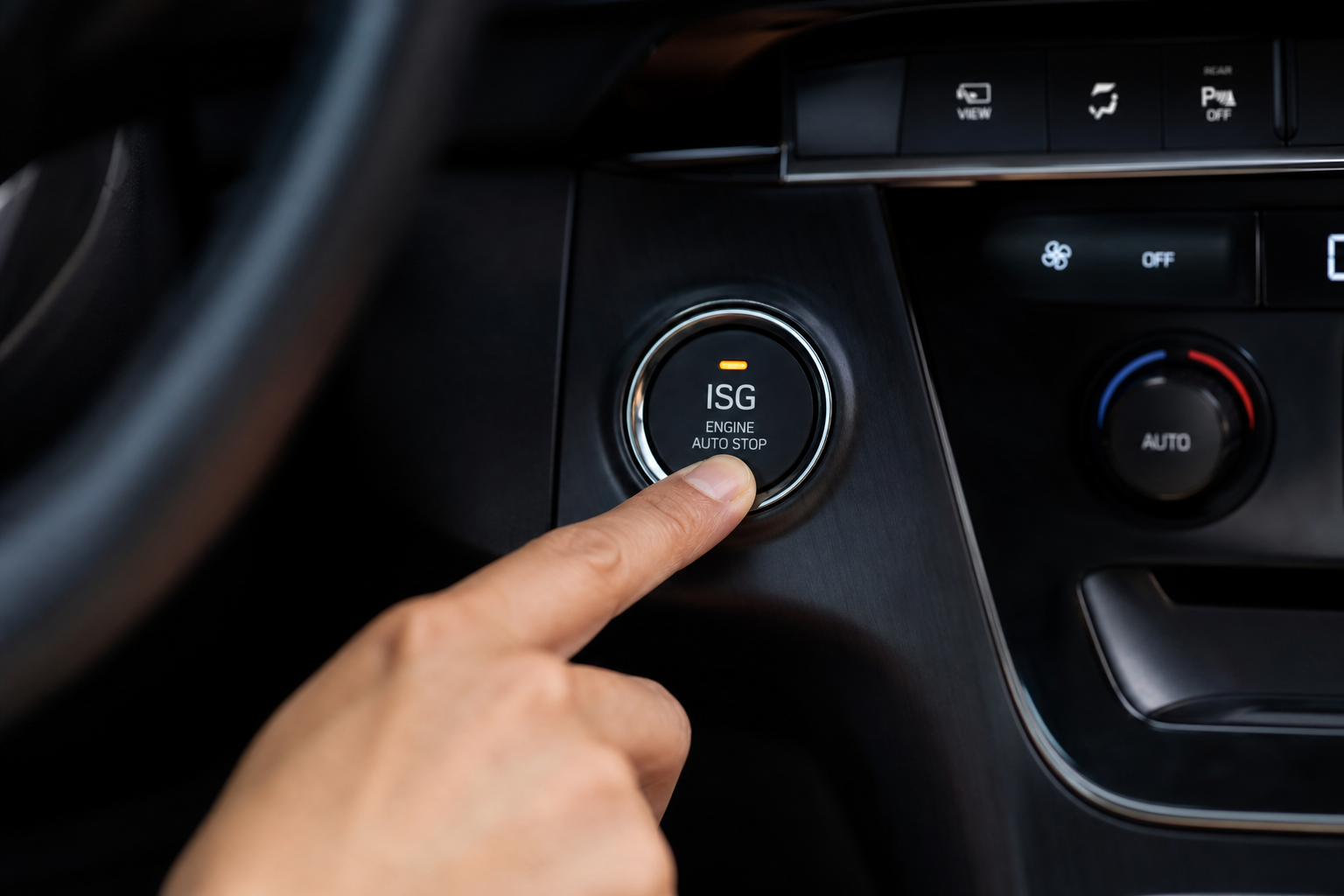 A finger pressing the ISG auto start-stop button on a Kia Carnival center console