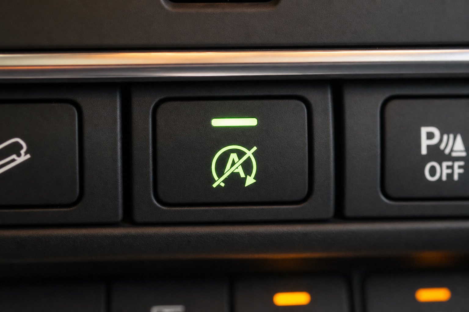 Close-up of an auto start/stop disable button on a car dashboard with indicator light glowing
