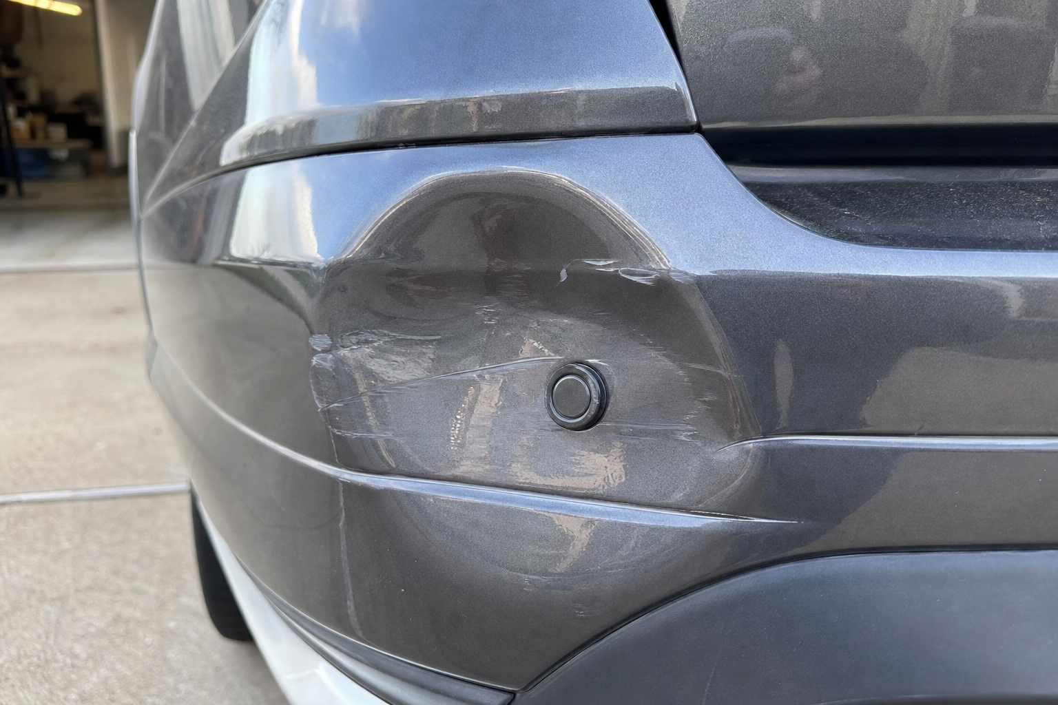 Damaged bumper with a misaligned parking sensor on a Ford Explorer