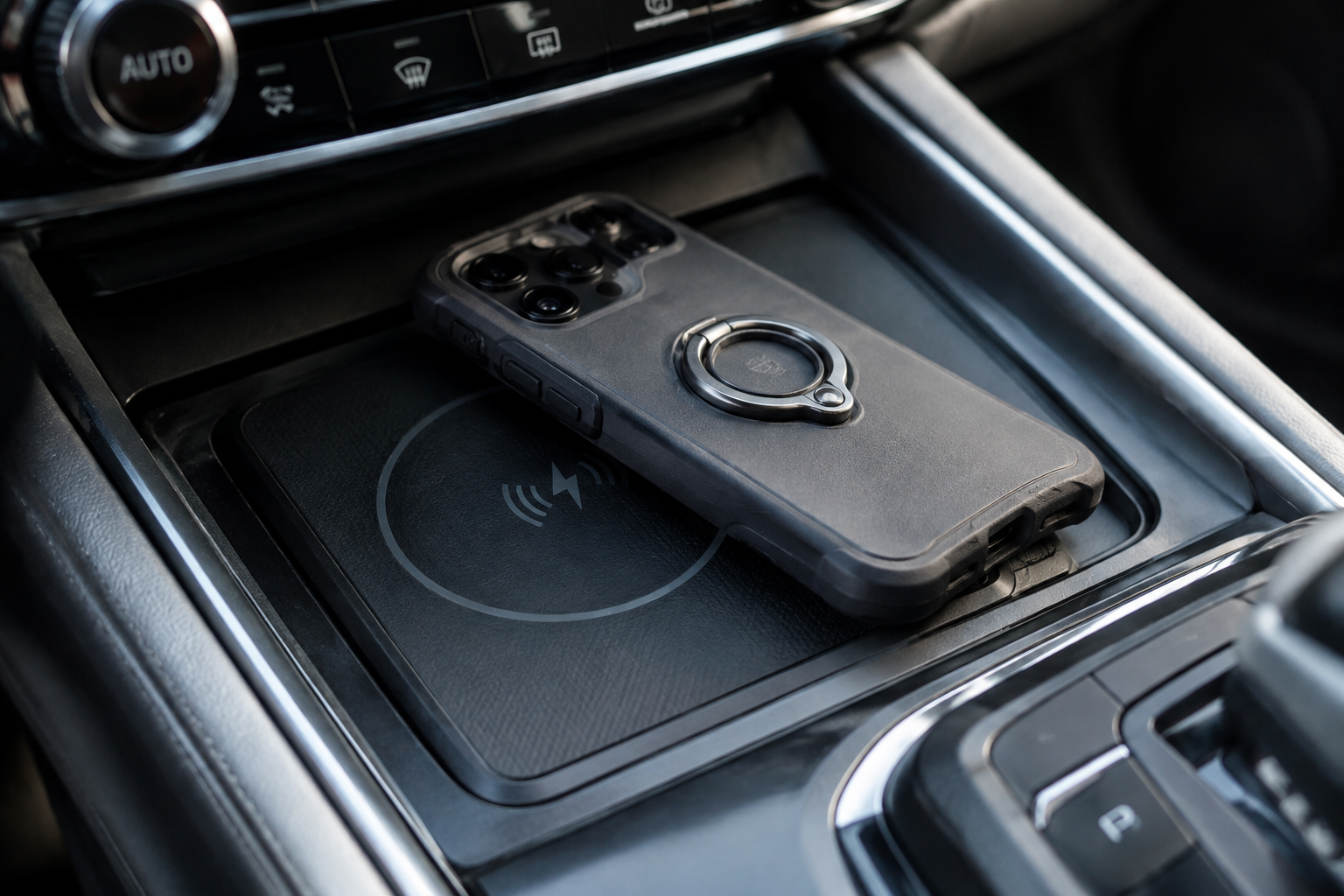 Smartphone with a thick case and metal ring holder sitting misaligned on a car wireless charging pad