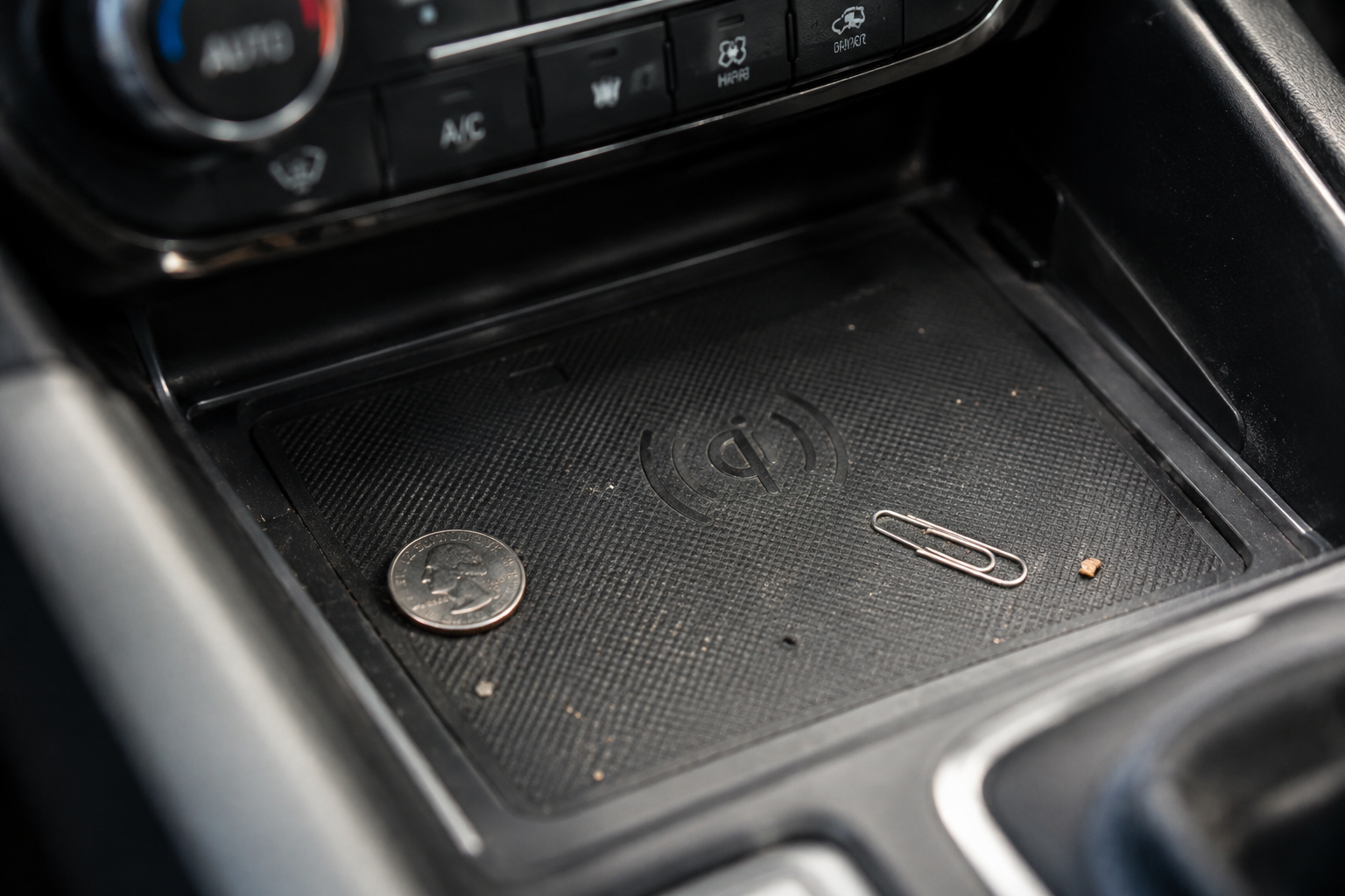 Coins and debris inside a car's wireless charging pad tray
