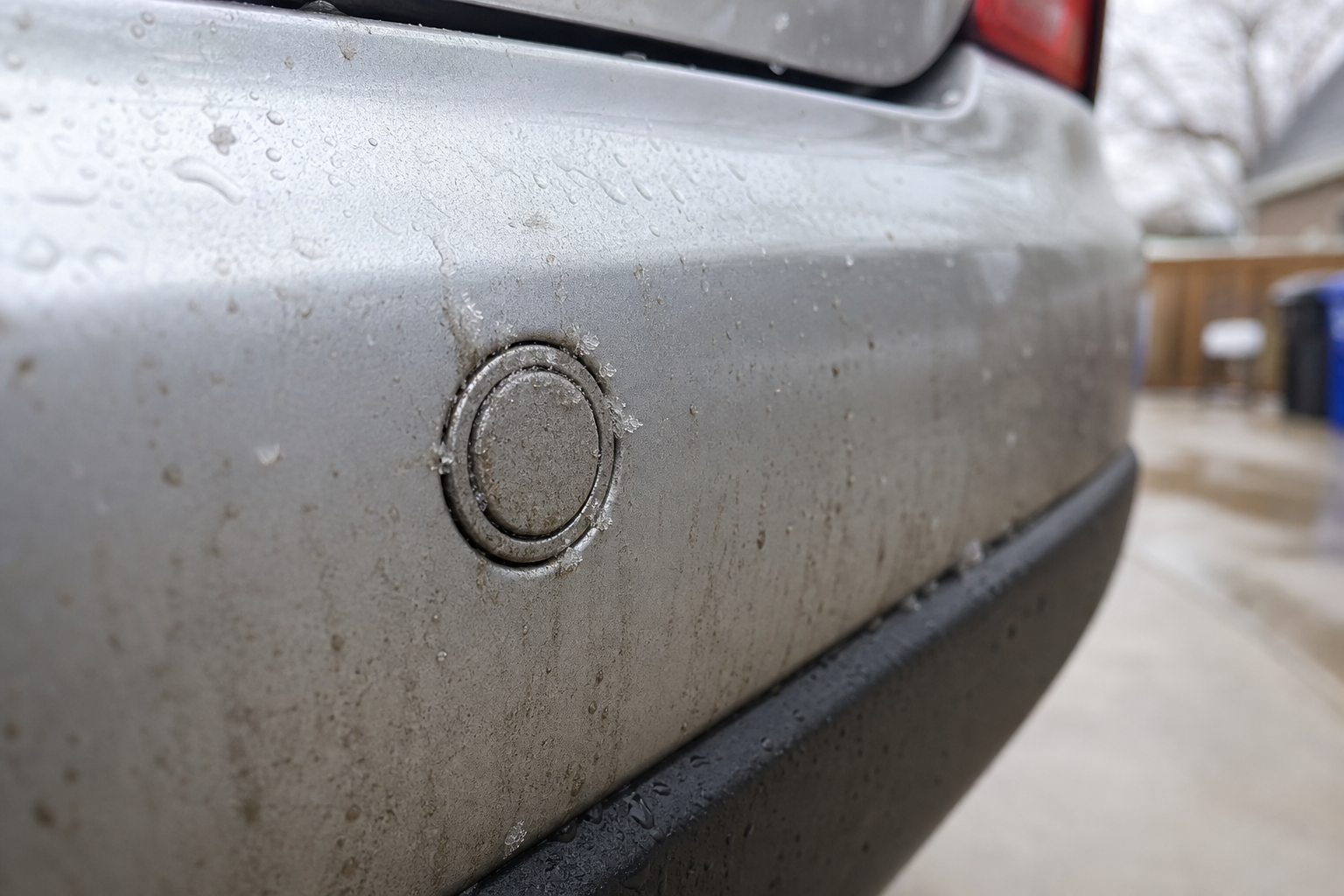 Close-up of a dirty, ice-covered parking sensor on a Toyota RAV4 bumper