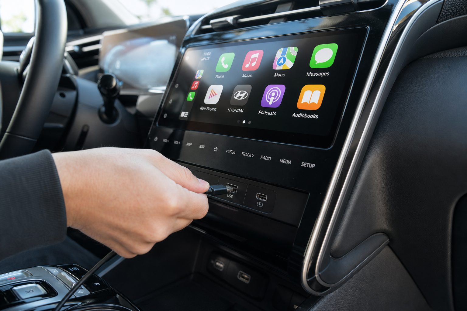 Hand plugging a USB cable into a Hyundai Tucson's infotainment system for wired CarPlay