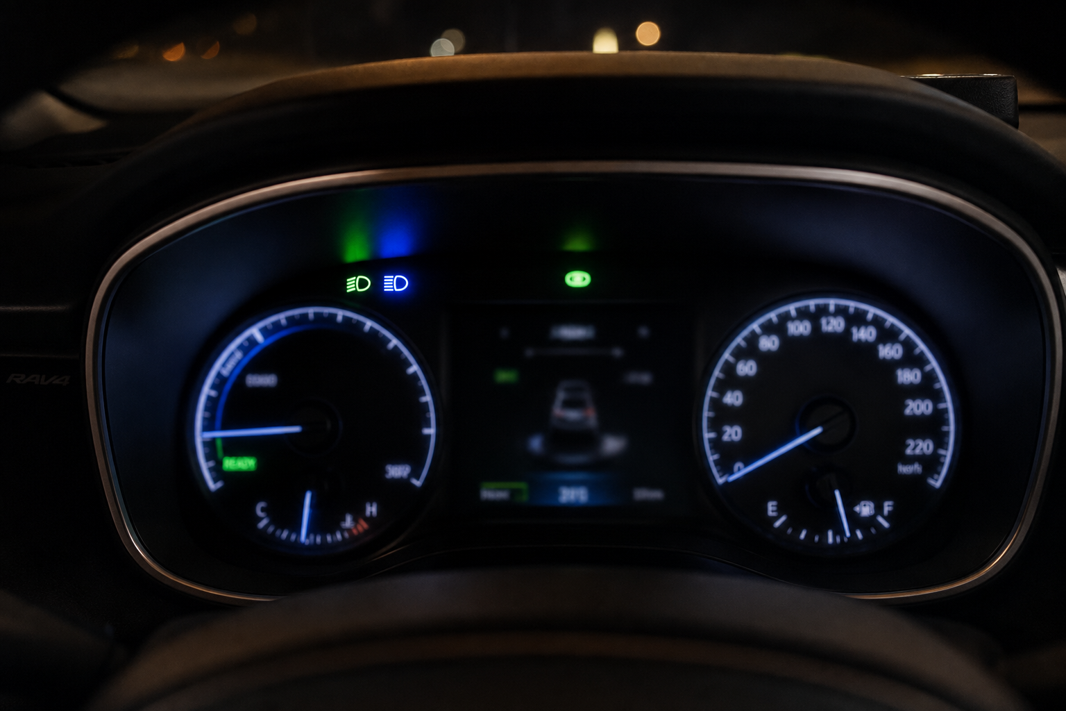 Toyota RAV4 dashboard instrument cluster showing headlight indicator lights at night