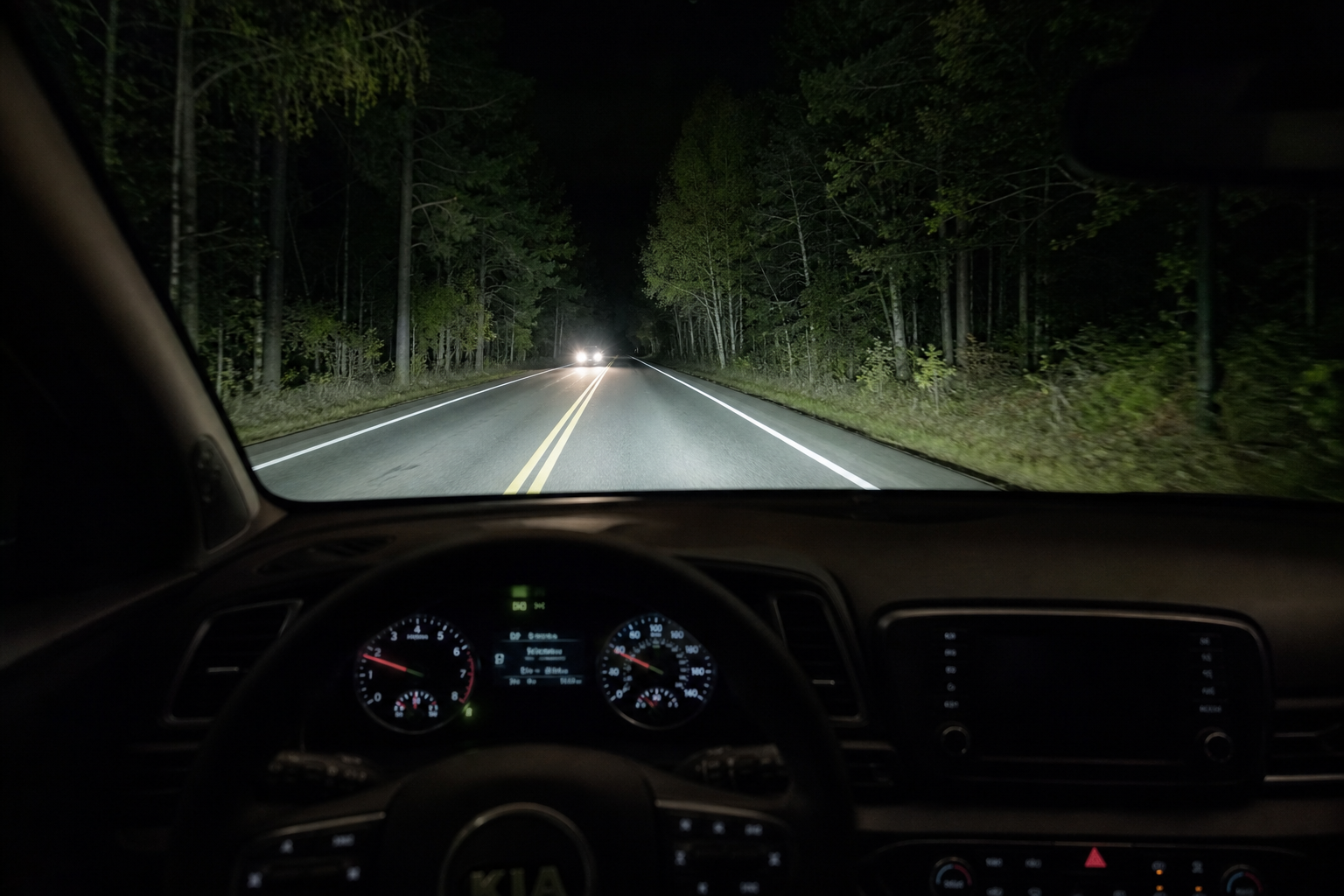 Kia Sportage driving at night with automatic high beams illuminating the road ahead