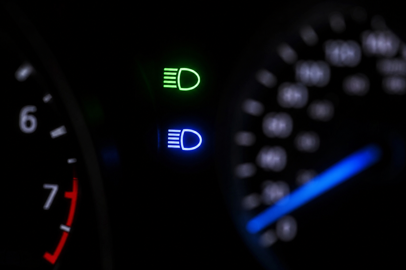 Illuminated dashboard indicator lights showing high-beam and headlight symbols in a Ford Explorer